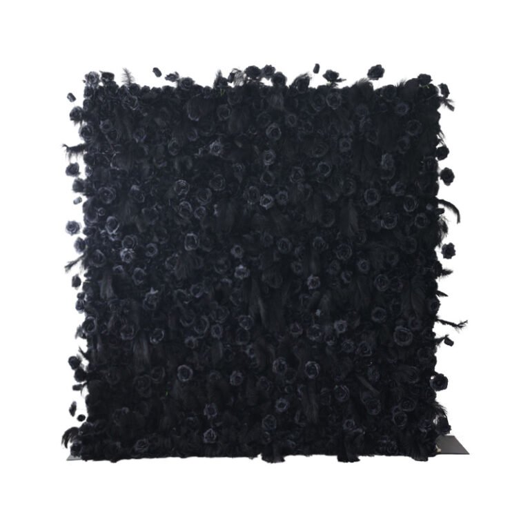 A square, black art piece covered in textured, three-dimensional floral and feather-like elements, creating a dense and intricate surface pattern against a white background.