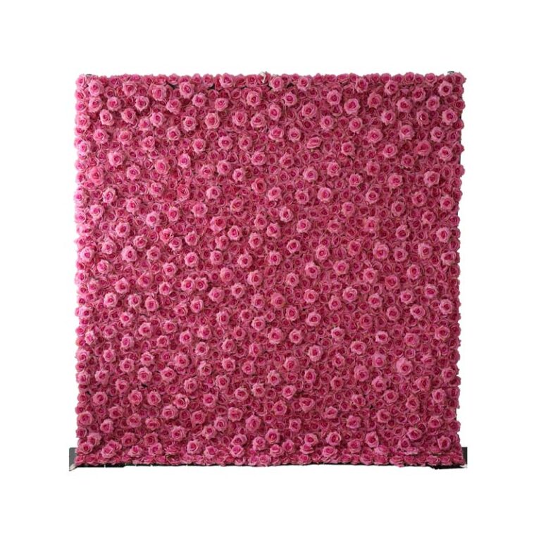 A square wall densely covered with vibrant pink artificial roses, creating a lush floral backdrop. The wall stands on a flat base against a plain white background.