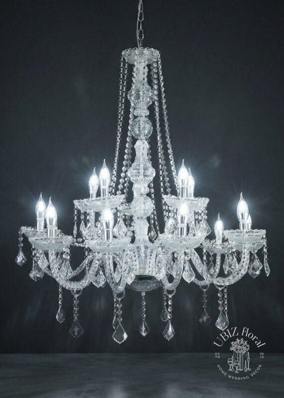The 15-Light Silver 2-Tier Crystal & Glass-Style Chandelier (3.2’H x 2.8’W) features crown top bead drapes and elegant crystal ornaments, hanging against a dark background. The brand logo is displayed in the bottom right corner.