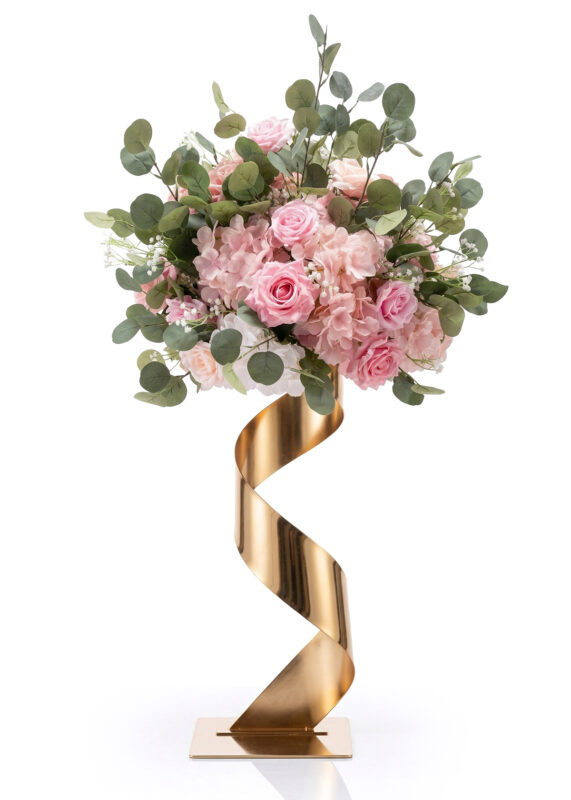 A stunning flower ball of pink roses and hydrangeas with eucalyptus leaves creates an elegant centerpiece in a tall, gold, spiral metal vase on a square base against a white background.