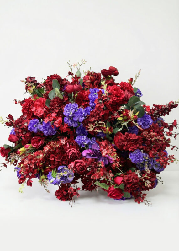 The Opulent Striking 24in Burgundy Flower Ball Centerpiece features red roses, dahlias, and purple accent flowers with lush greenery, making a stunning wedding centerpiece. Comes in a 2 pack and stands out beautifully against a white background.
