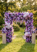 The Burgundy Red Rose Flower Arch Backdrop, 8ft x 8ft, creates a stunning romantic wedding setting outdoors with lush burgundy flowers, pastel accents, and serves as an elegant ceremony decor focal point-860830.
