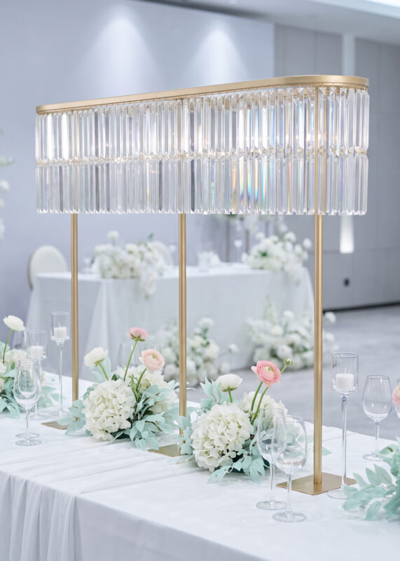 A Gold Double-Layer Crystal Fringe Wedding Centerpiece Stand, Glamorous & Radiant 51in Tall Oval Design on a wedding table with white floral arrangements and candles.