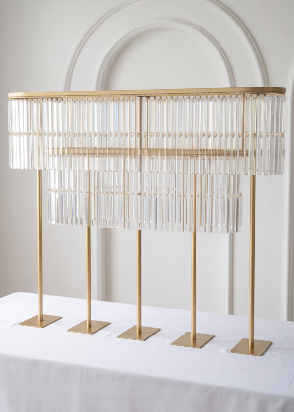 A 51.2in Gold Double-Layer Crystal Fringe Wedding Centerpiece Stand with an oval design, featuring hanging prisms and five vertical support posts on a white tablecloth.